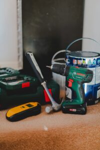 Contractor in work attire using basic hand tools inside a commercial building maintenance area.