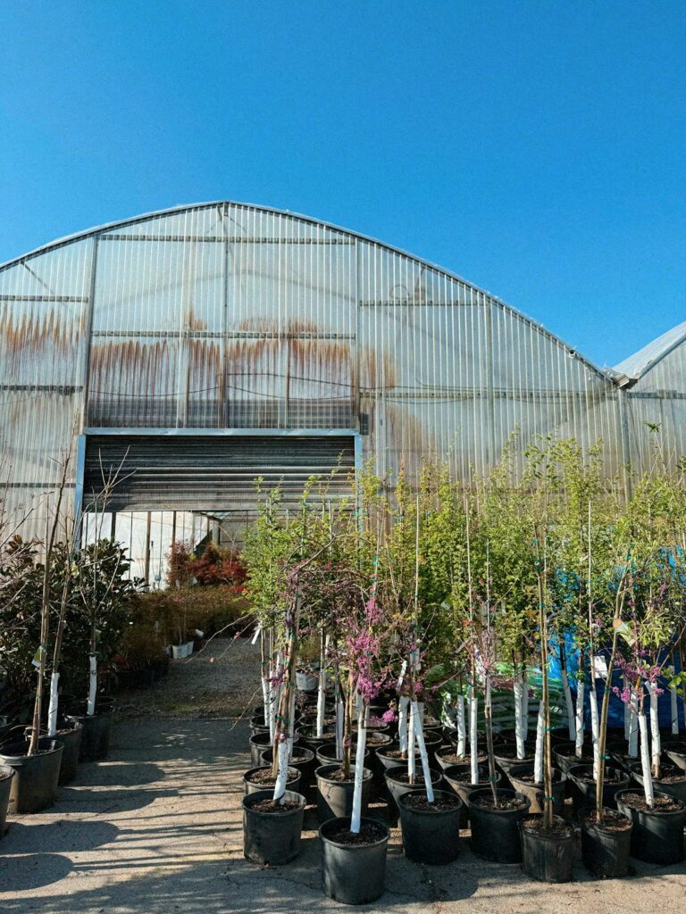 A grounds crew inspects shrubs, mulch, irrigation lines, and young trees around a commercial building.